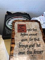 Wooden plaque with burnt wood finish and a quote printed in black calligraphy style font on a beige background.