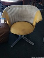 Front view of swivel chair showing mustard yellow seat and beige backrest upholstery with stains and discoloration.
