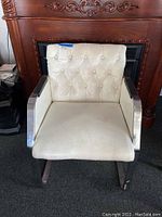 Front view of white vinyl chair showing tufted backrest, chrome frame, and padded armrests