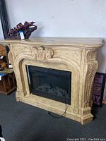 Front view of the solid wood electric fireplace with carved decorative mantle and electric firebox with faux logs.