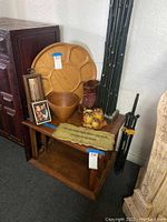 Overview photo showing wood lazy Susan on top shelf, wood boot vase, ceramic owls, wood bowl, bamboo art poles standing behind, tripod, and wooden wall plaque on lower shelf.