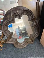 Full view of dark brown wooden quatrefoil wall mirror with layered molding frame