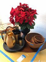Wooden nested bowls next to three metal pitchers and a small metal container on a gray tray.