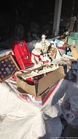 Photo showing Coca Cola collectible items including bears, pens, a red radio, small signs, lamp, and toy truck in a box