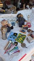 Wide view of lot laid on white sheet including plush doll, handkerchiefs, small boxes, glass decanter, and various stirrers.