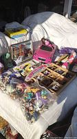 Image showing assorted toys on white couch including boxed RB Royal Breed horses, pink Barbie toy car, and other small figures spread out