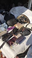 Photo showing the full lot including black handbag, leopard print lunch bag, belts, and various wallets and clutches.