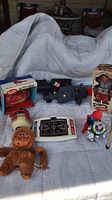 Lot overview showing all vintage toys including mechanical skipping monkey, Salty piggy bank, Tommytronics basketball game, Ghostbusters toys, monkey and horse figurines.