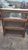Full view of very old solid oak three shelf display cabinet with beveled glass front panels.