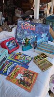 Photo showing the Omega Virus board game box, Silverhawks lunch box, Ninja Turtle mechanical toy, Pokemon handbooks, and tin with collectible figures.