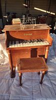 Front view of child's piano with music stand and matching piano bench included.