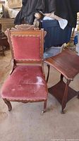 Photo showing full view of vintage wooden chair with red velvet upholstery and a matching wooden side table