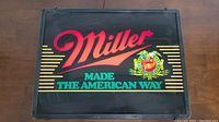 Rectangular Miller bar light showing red Miller logo, turquoise 'Made The American Way' text, and branded emblem on black background.