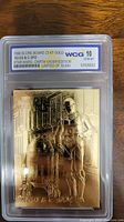 Close-up of gold-plated Star Wars collectible card featuring R2-D2 and C-3PO inside graded protective case with WCG 10 GEM-MT label