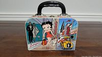 Front side showing Betty Boop character with shopping bags, a cityscape background, and a yellow car with a dog.