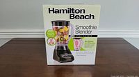 Front view of box showing Hamilton Beach Smoothie Blender with fruits in the jar, highlighting 10 speed settings and suitability for smoothies, shakes, and icy drinks.