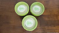 Top view of three citronella candles in green ceramic pots with plastic lids showing Everyday Essentials labels