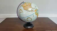 Globe front view showing Americas and part of Europe, mounted on black stand.