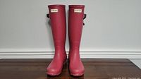 Front view of both pink Hunter rain boots, standing upright showing logos.