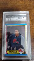 Front view of the 1989 Joe Sakic rookie hockey card graded SMA 5 in protective casing