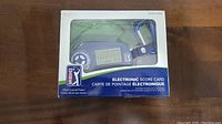 Photo of PGA Tour electronic score card in original packaging showing device and score display.
