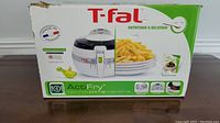 Front of box showing T-fal ActiFry air fryer, serving suggestions with fries, and product details