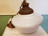 Front view showing white flared milk glass shade and rusted metal canopy