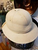 Light tan British pith helmet with stitched band and ventilation eyelets shown from front angle