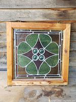 Full view of antique stained glass window framed in wood, mounted on a wooden background.