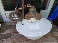 Fixture laid on wooden surface showing full pendant light with milk glass shade, metal canopy and chain