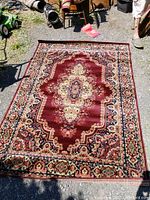 Full view of the large rectangular floral rug laid flat on ground outdoors showing overall color and design.