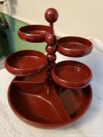 Side angle view showing the five elevated circular bowls attached to the central pole and the divided base tray with two compartments.