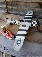 Both items showing the plastic boat and metal plane side by side on a wooden surface