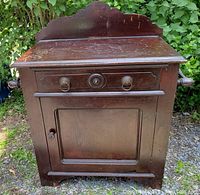 Front view of vintage pine washstand showing drawer and cabinet door with original dark-stained finish.