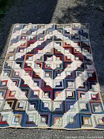 Full view of the vintage handmade quilt laid flat showing the overall geometric log cabin patchwork design with a central diamond shape.