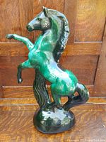 Front view of the green and dark blue glazed Blue Mountain Pottery rearing horse figurine, showing its height and detailed form.