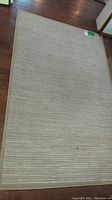 Photo of cream color 4x6 rug laid out on hardwood floor showing woven texture and overall condition.