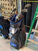 Photo showing full Maxfli golf bag with numerous golf clubs stored inside, showing worn condition.