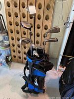 Full view of golf bag with multiple golf clubs inside including woods and irons.