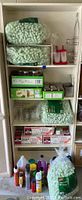 Full shelf view showing mason jars boxes, packing peanuts, lightbulb boxes, some cups and container contents on shelves, as well as cleaning supplies below shelf.