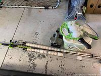 Wide photo showing fishing rod, ball shooter device, plastic bin with balls, paddle ball paddles