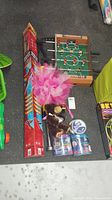 Photo of assorted toys including Sky Rider pogo stick, mini foosball table, colorful kite, plush monkey, and Play-Doh cans arranged on floor.