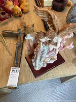 Photo showing the cross and angel sculptures on wooden table with visible wear and patina on items