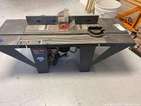 Full view of Vermont American router table with mounted router and assorted bits holder on the table surface.