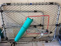 Photo showing the rectangular metal frame with black netting. Includes green foam padding and red metal frame component.