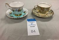 Photo showing the Royal Albert and Colclough bone china cup and saucer sets side by side on a flat surface.