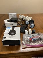 Overview of all items on table: headphones box, Apple TV unit and box, CD-R pack, extension cord, mice, adapters, chargers, cables.