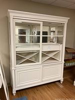 Full front view of white painted china hutch with sliding glass doors and mirror back, showcasing upper and lower sections and flooring