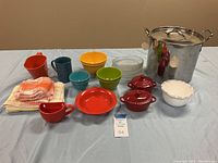 Overview photo showing all kitchenware including the stewpot, bowls, mugs, hand towels, and sifter grouped together on table
