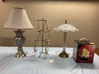 Photo showing the brushed nickel table lamp with pleated shade, vintage 3-tiered icicle candle tree, and boxed Homedics relaxation foundation on a table.